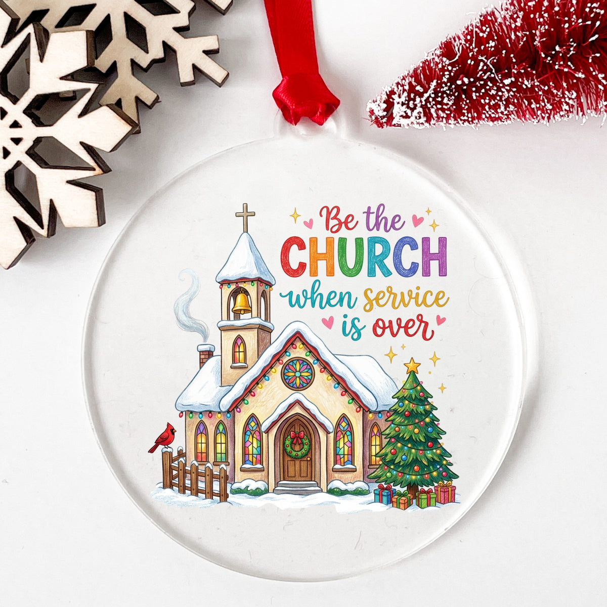 Be The Church Christmas Quote UV DTF sticker applied to a clear round acrylic ornament with a red ribbon