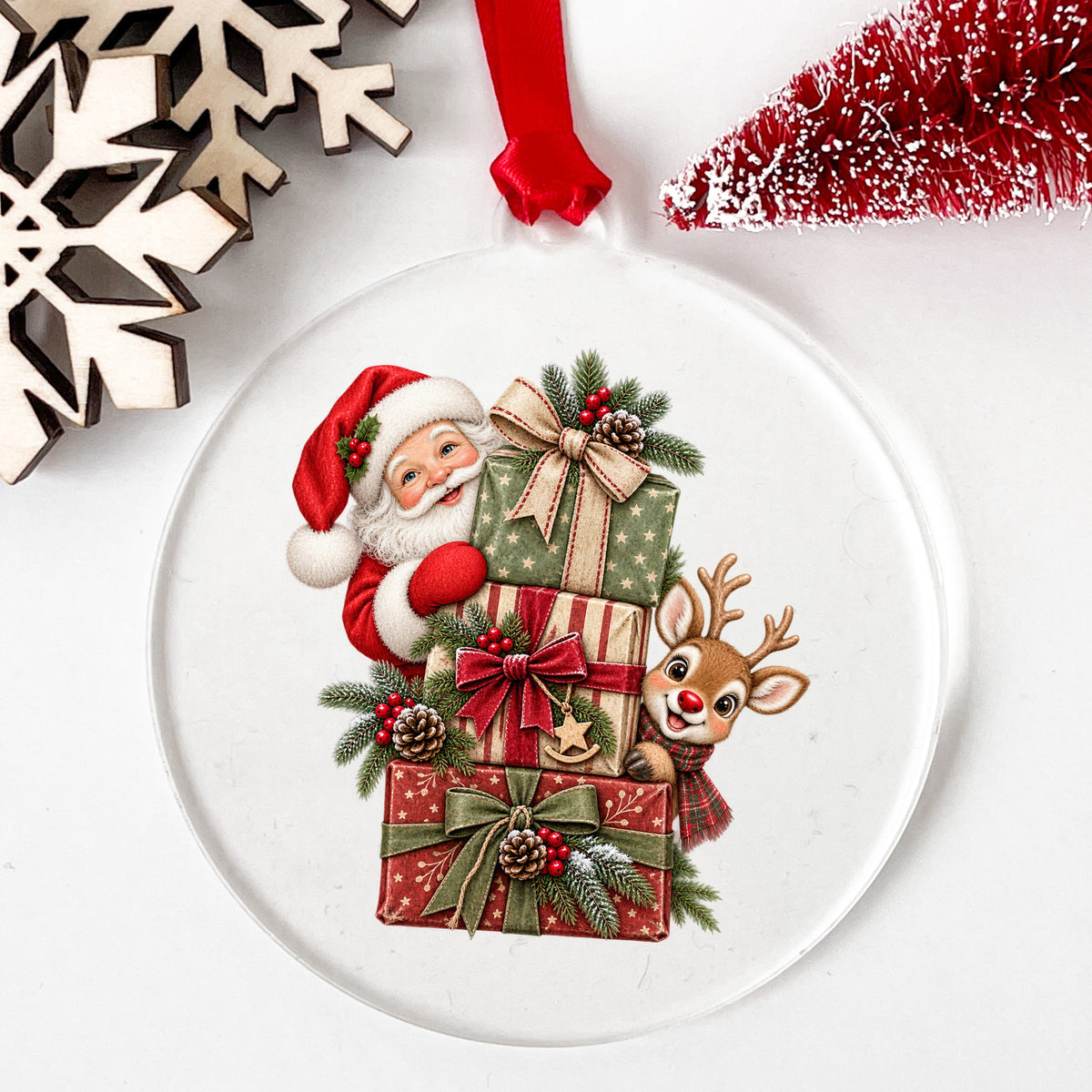Santa And Reindeer With Stacked Gifts UV DTF sticker applied to a clear round acrylic ornament with a red ribbon