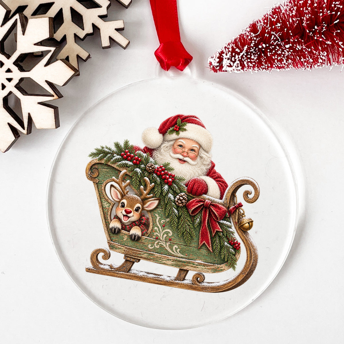 Santa In Green Sleigh With Reindeer UV DTF sticker applied to a clear round acrylic ornament with a red ribbon