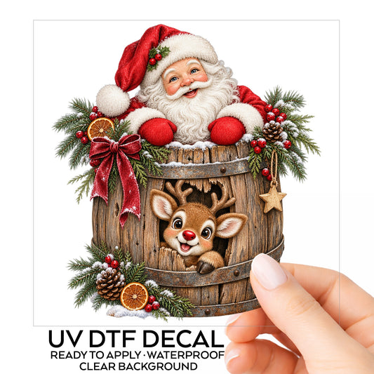 Santa And Reindeer In Wooden Barrel UV DTF sticker on its backing card, held in hand