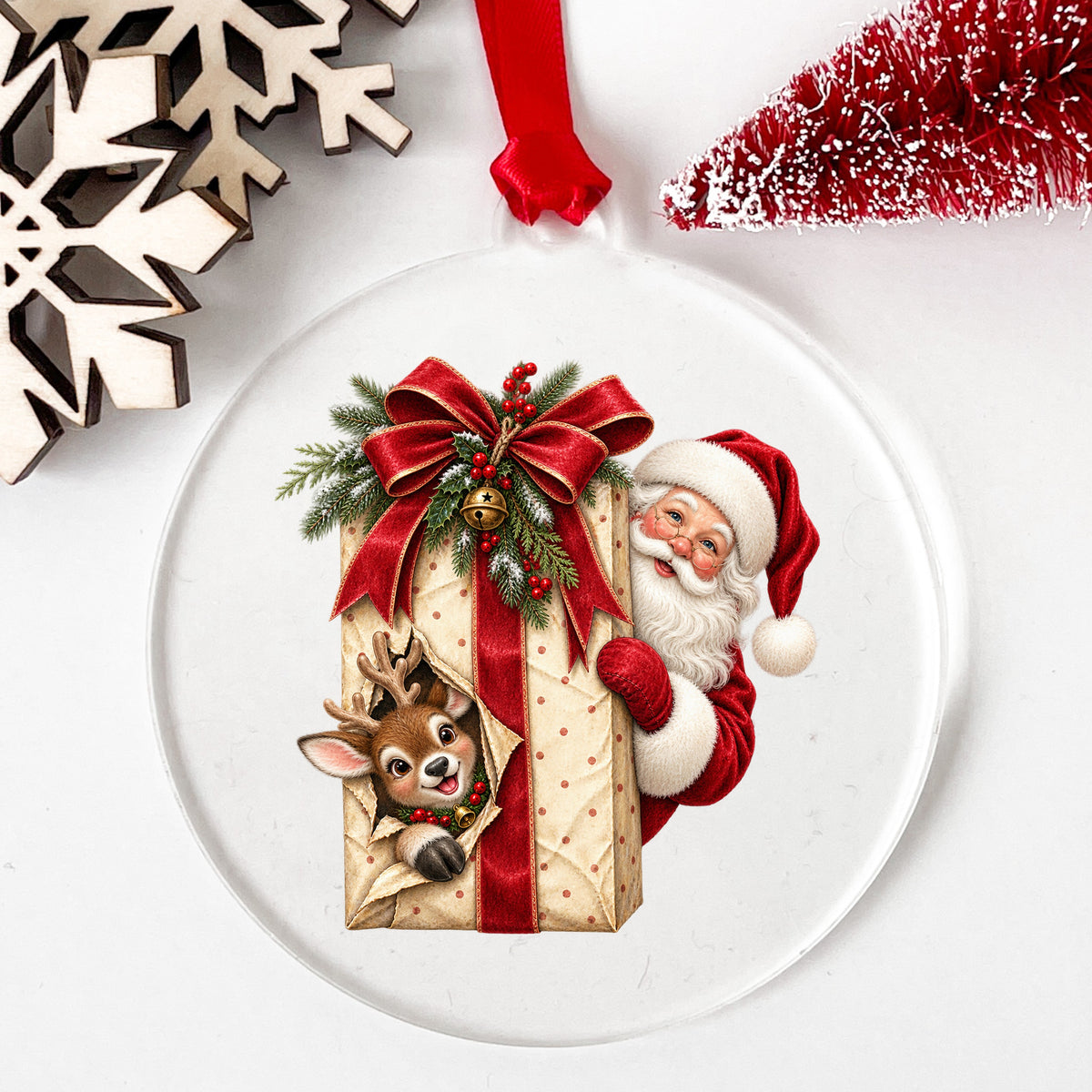 Santa Behind Polka Dot Gift With Reindeer UV DTF sticker applied to a clear round acrylic ornament with a red ribbon