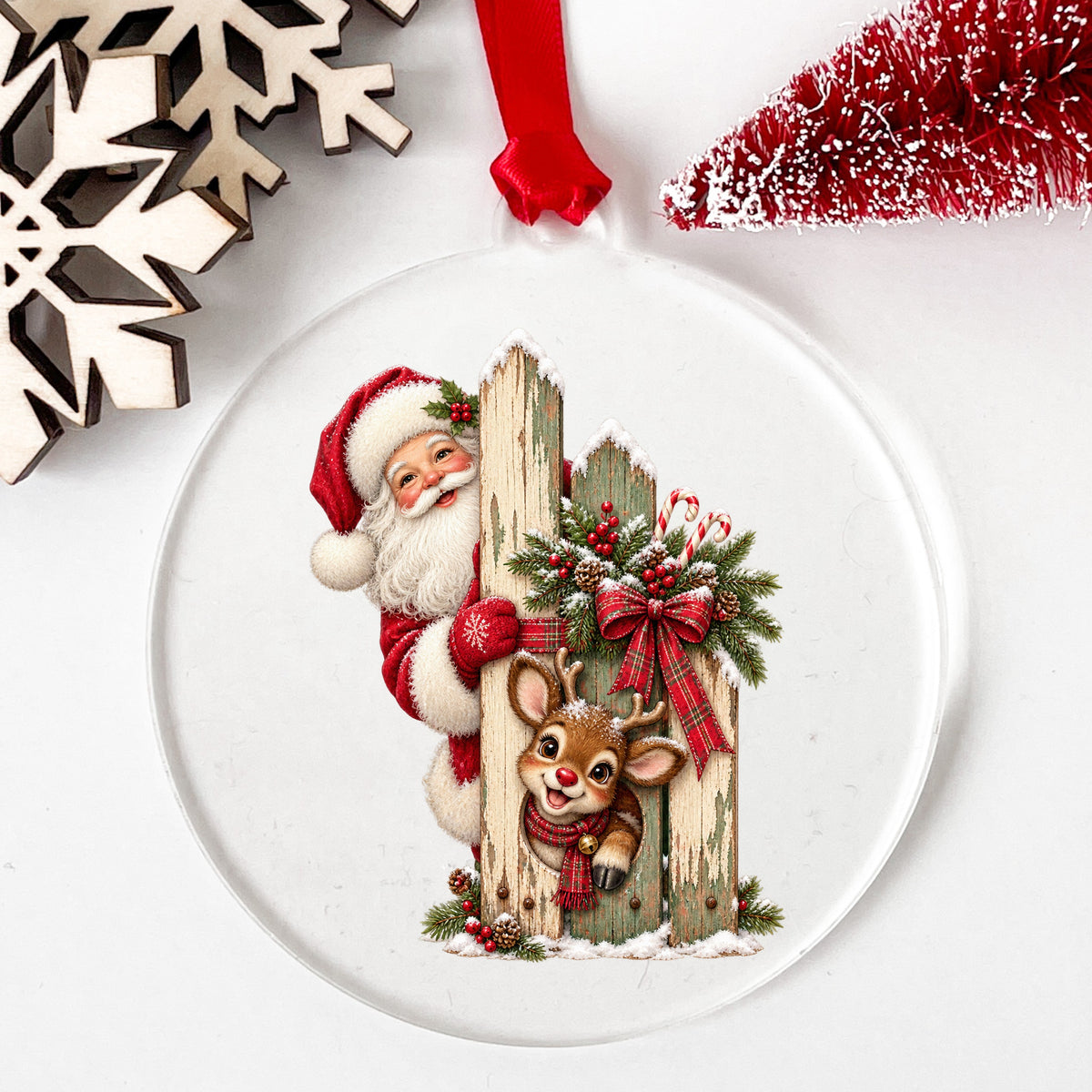 Santa And Reindeer Behind Picket Fence UV DTF sticker applied to a clear round acrylic ornament with a red ribbon