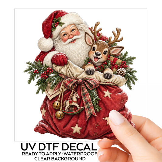 Santa With Red Toy Sack And Reindeer UV DTF sticker on its backing card, held in hand
