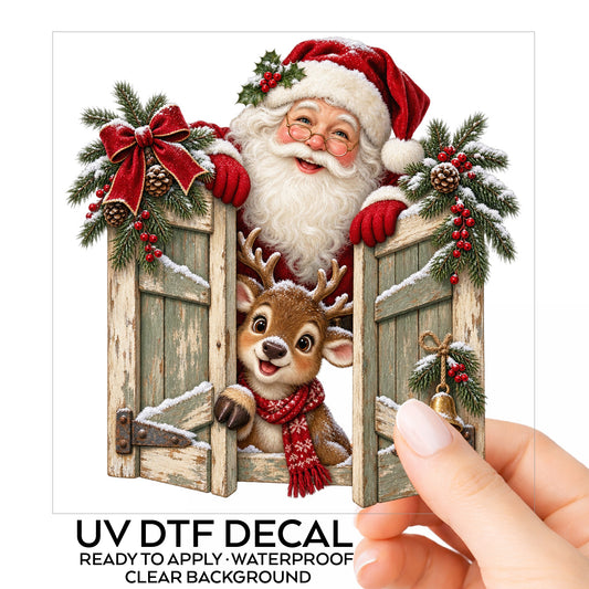 Santa And Reindeer Behind Wooden Shutters UV DTF sticker on its backing card, held in hand