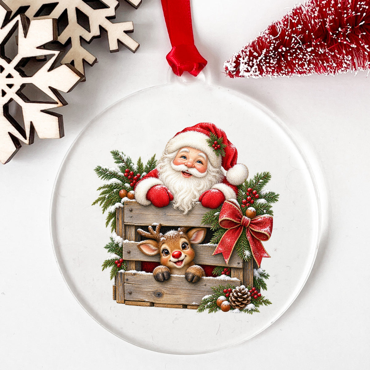 Santa And Reindeer With Wooden Crate UV DTF sticker applied to a clear round acrylic ornament with a red ribbon