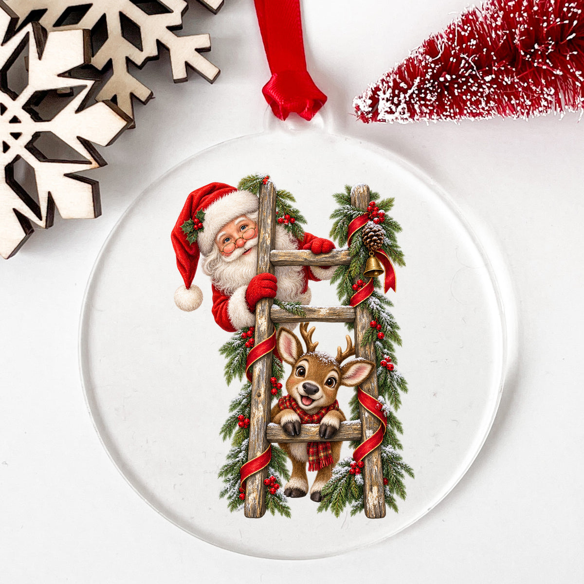 Santa And Reindeer On Wooden Ladder UV DTF sticker applied to a clear round acrylic ornament with a red ribbon