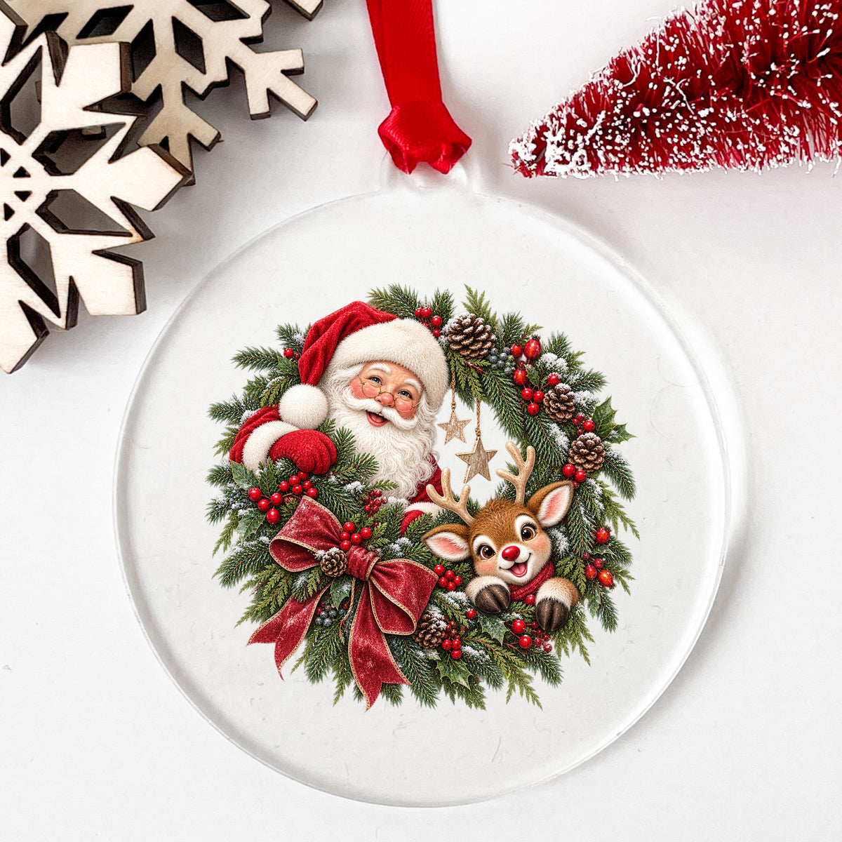 Santa And Reindeer In Berry Pinecone Wreath UV DTF sticker applied to a clear round acrylic ornament with a red ribbon