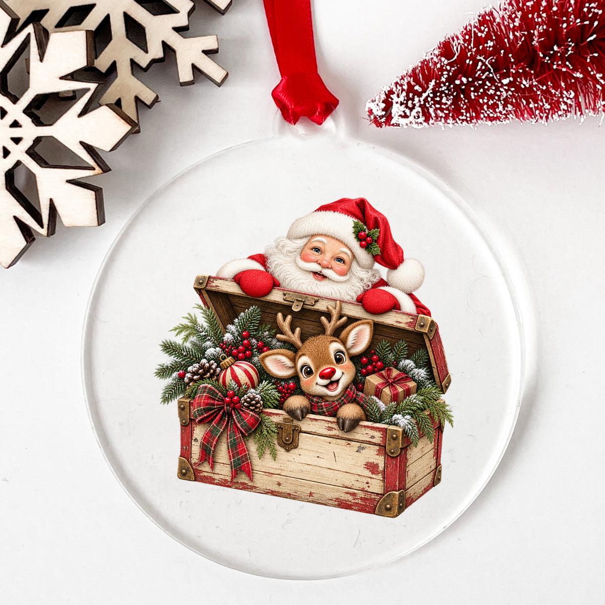 Santa And Reindeer In Vintage Toy Chest UV DTF sticker applied to a clear round acrylic ornament with a red ribbon