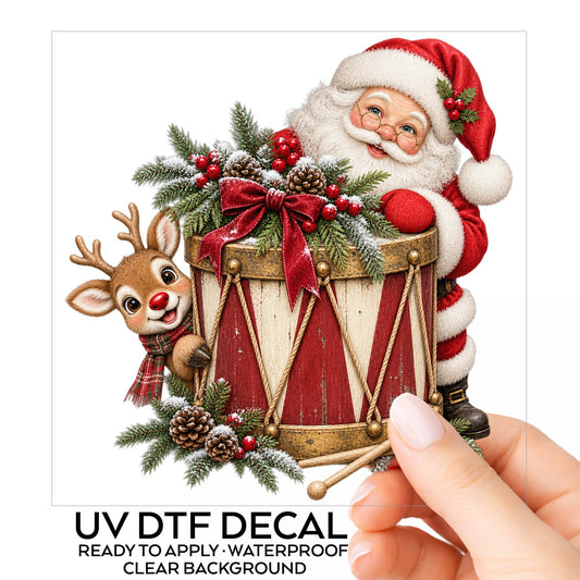 Santa And Reindeer With Vintage Toy Drum UV DTF sticker on its backing card, held in hand