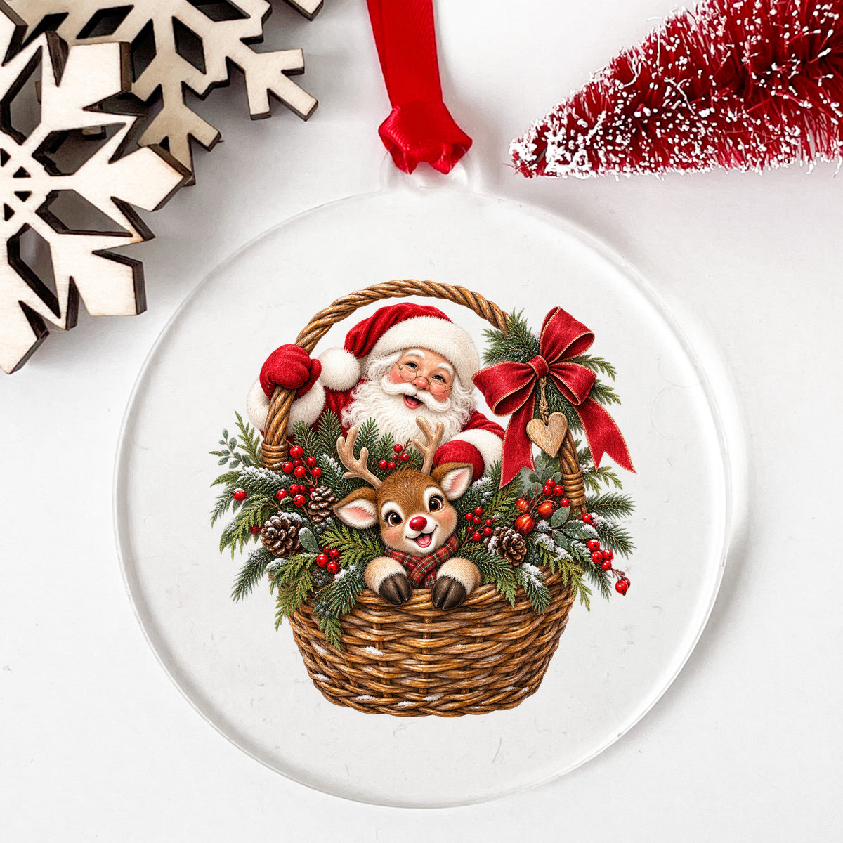 Santa And Reindeer In Wicker Basket UV DTF sticker applied to a clear round acrylic ornament with a red ribbon