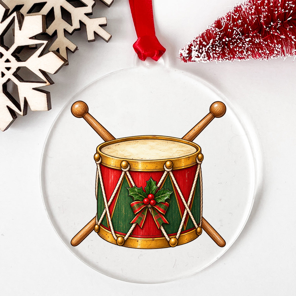 Vintage Toy Drum With Drumsticks UV DTF sticker applied to a clear round acrylic ornament with a red ribbon