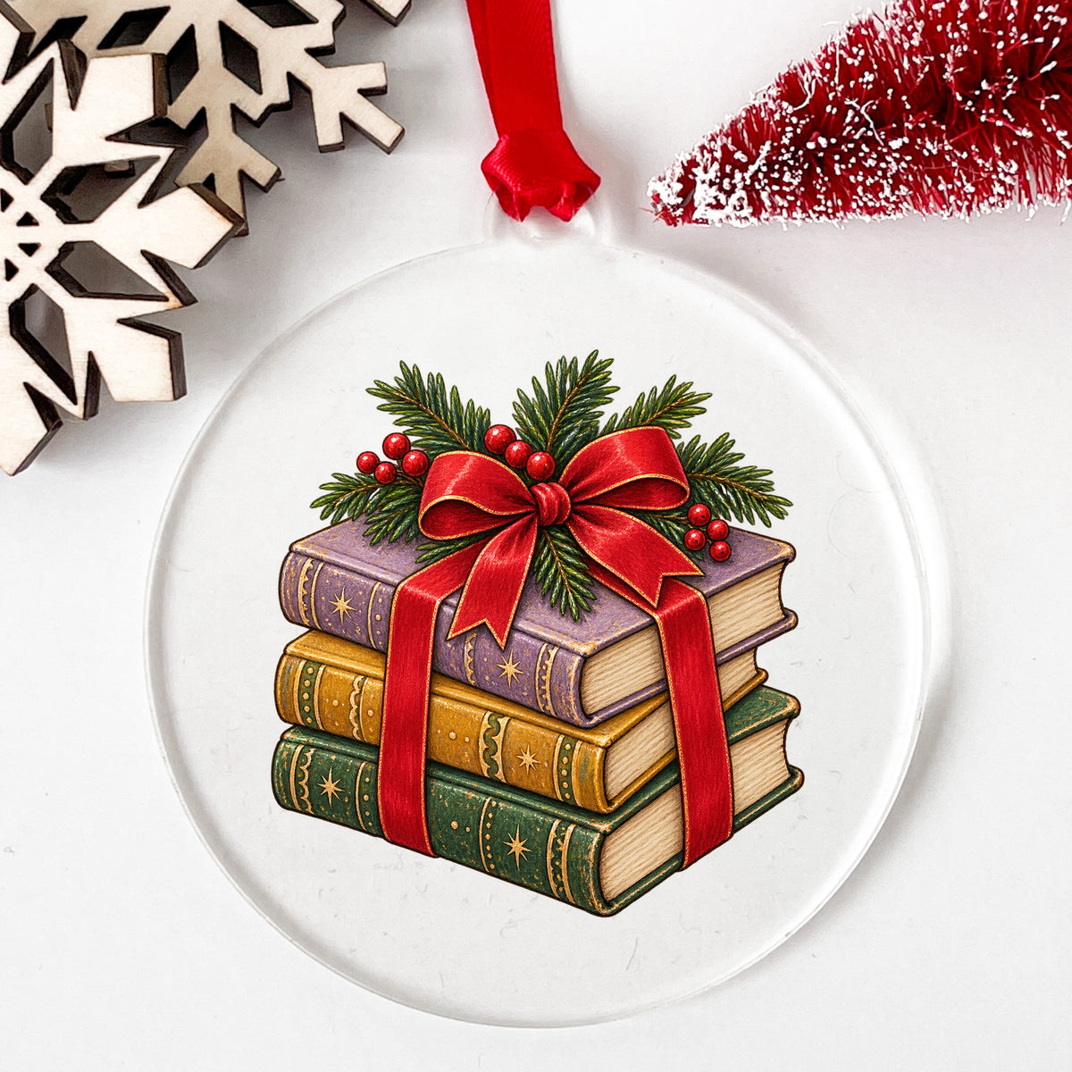 Christmas Book Stack With Red Bow UV DTF sticker applied to a clear round acrylic ornament with a red ribbon