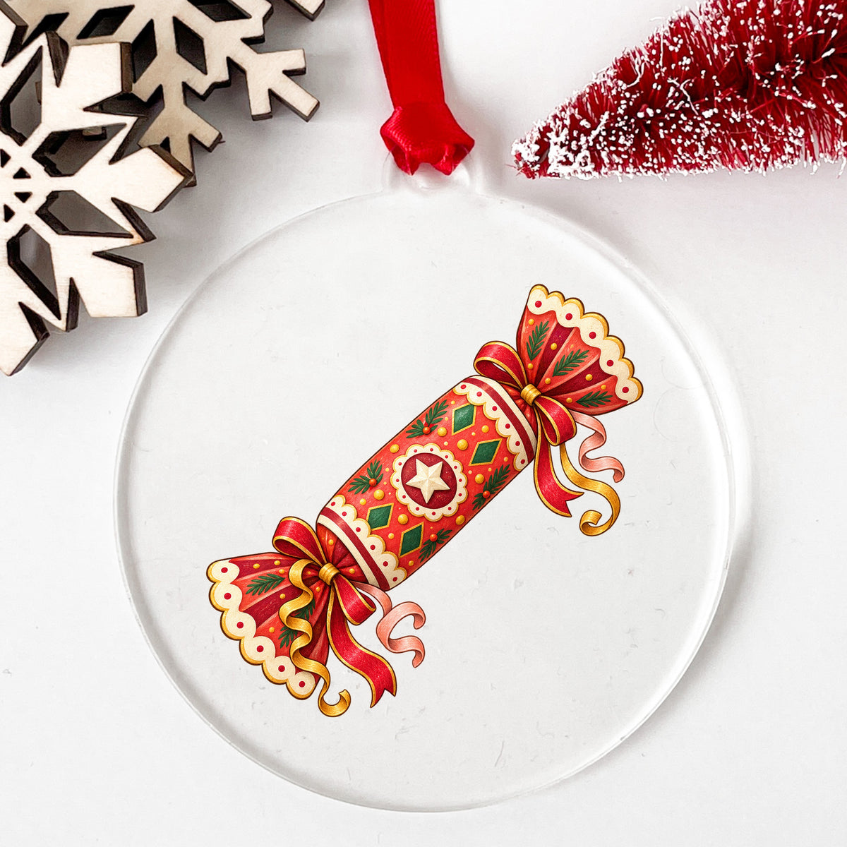 Christmas Cracker With Ribbon Bows UV DTF sticker applied to a clear round acrylic ornament with a red ribbon
