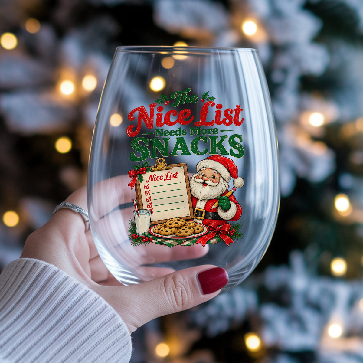 Nice List Needs More Snacks Santa UV DTF sticker applied to a stemless wine glass held in hand