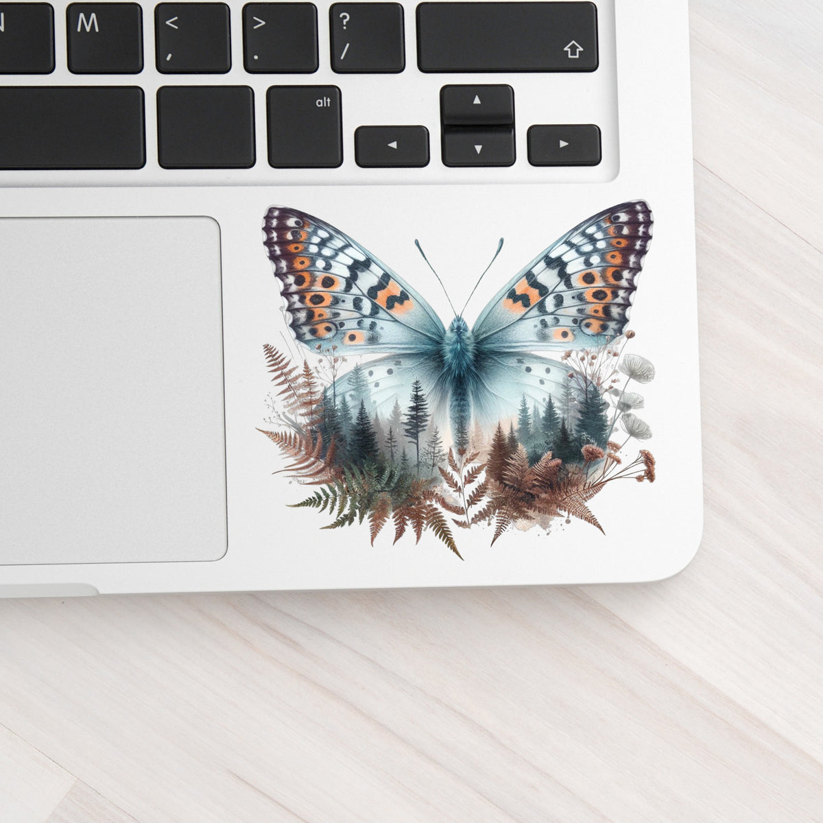 Fern Butterfly UV DTF sticker applied to a silver laptop beside the keyboard