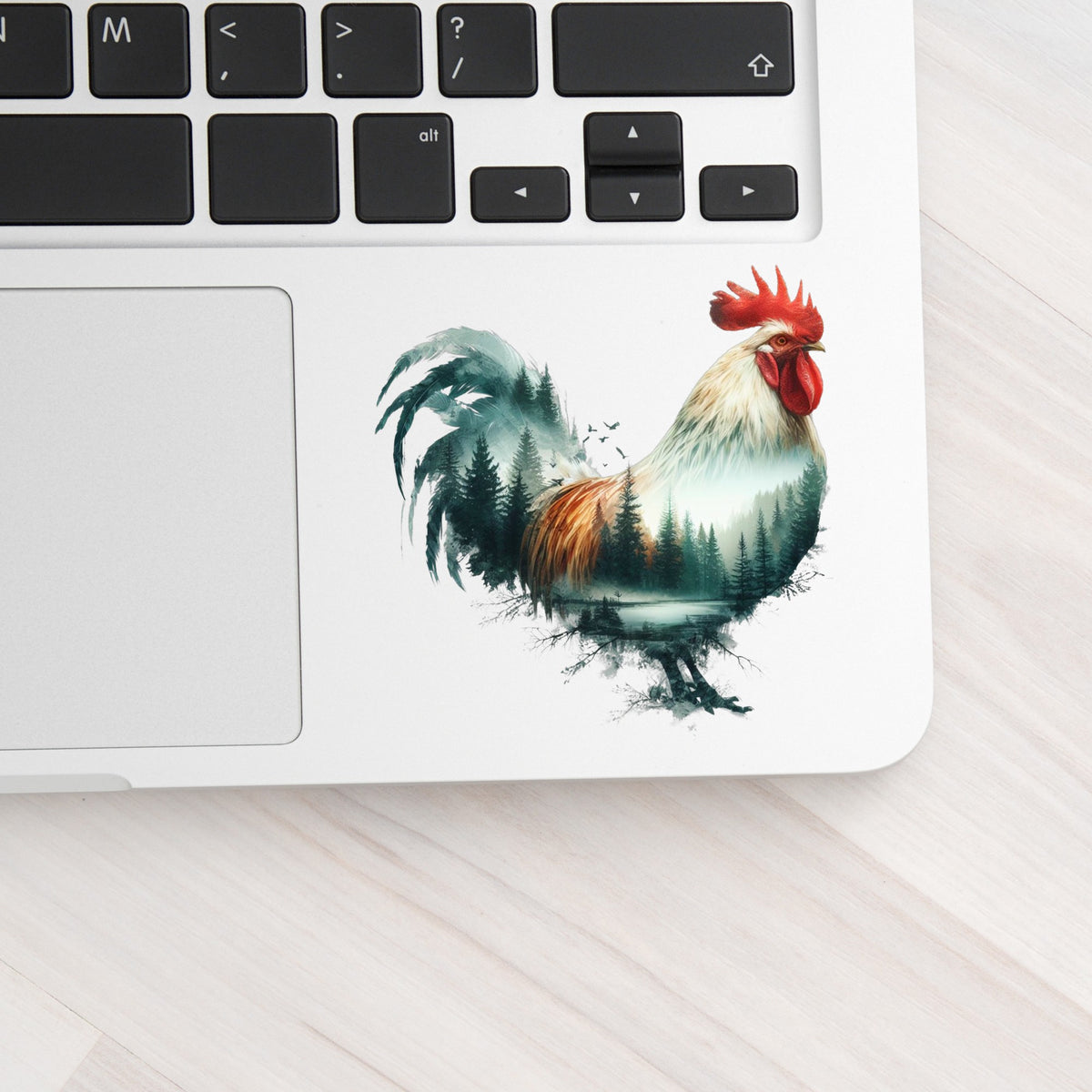 Forest Lake Rooster UV DTF sticker applied to a silver laptop beside the keyboard