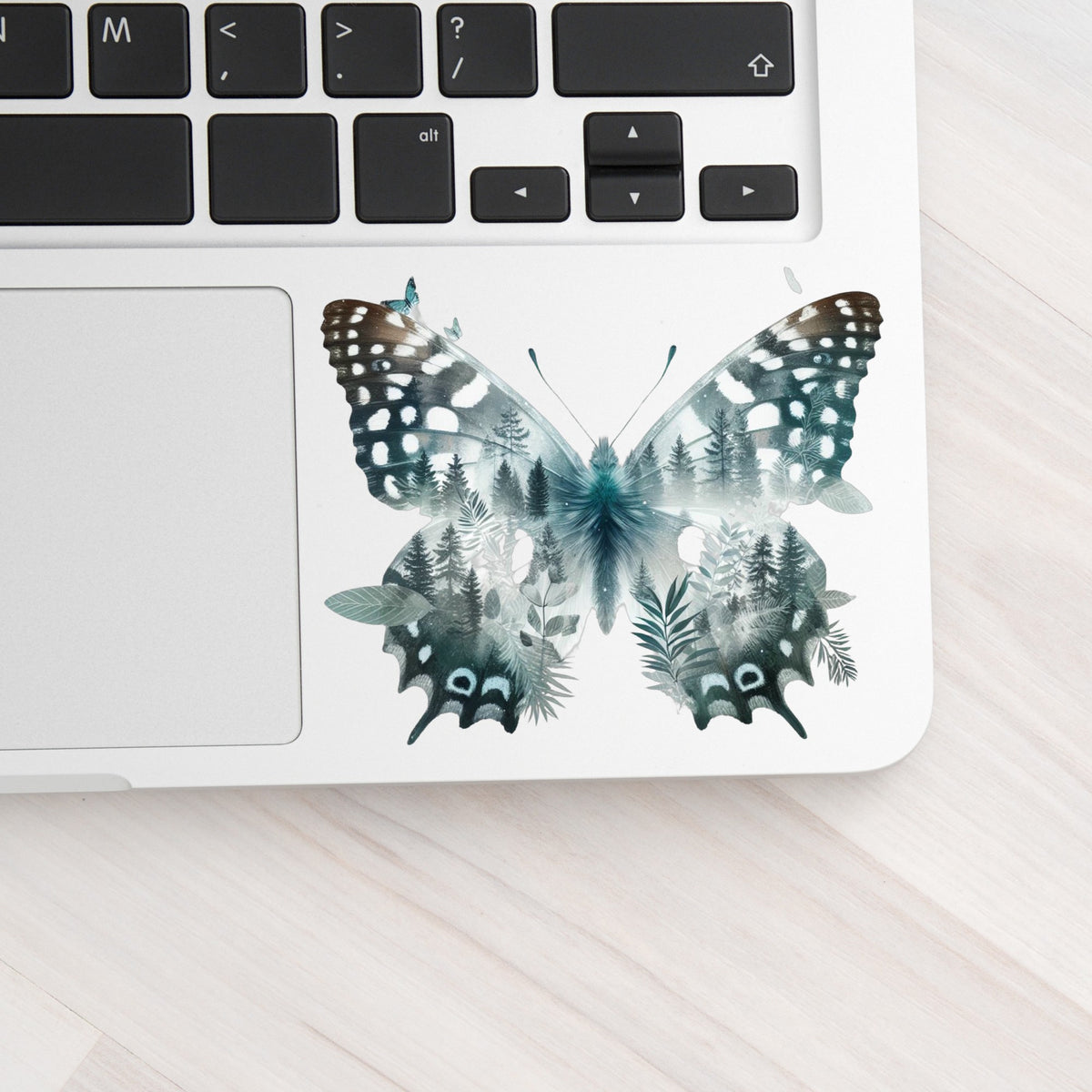 Black White Butterfly UV DTF sticker applied to a silver laptop beside the keyboard