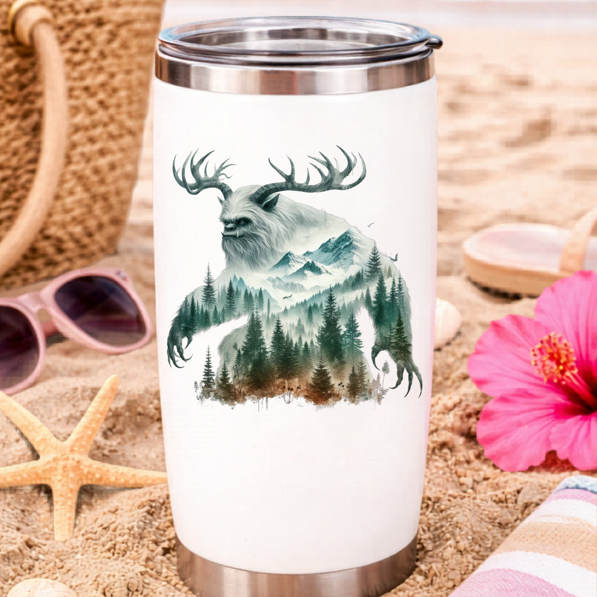 Antlered Mountain Bigfoot UV DTF sticker applied to a white travel tumbler on beach sand