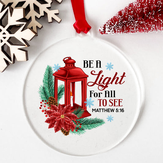 Be A Light Christmas Lantern UV DTF sticker applied to a clear round acrylic ornament with a red ribbon