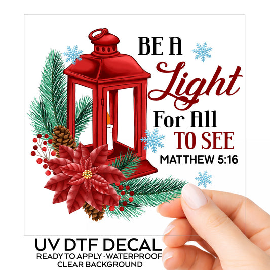 Be A Light Christmas Lantern UV DTF sticker on its backing card, held in hand