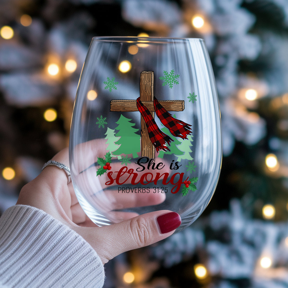 She Is Strong Christmas Cross UV DTF sticker applied to a stemless wine glass held in hand