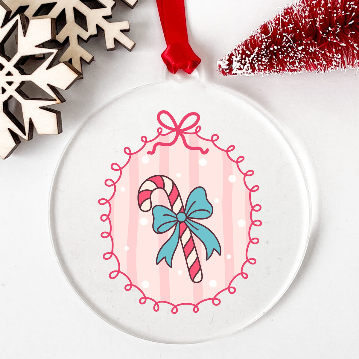 Coquette Candy Cane UV DTF sticker applied to a clear round acrylic ornament with a red ribbon
