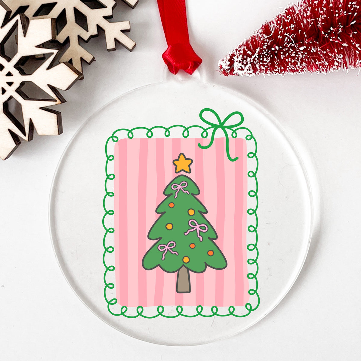 Coquette Pink Bow Christmas Tree UV DTF sticker applied to a clear round acrylic ornament with a red ribbon