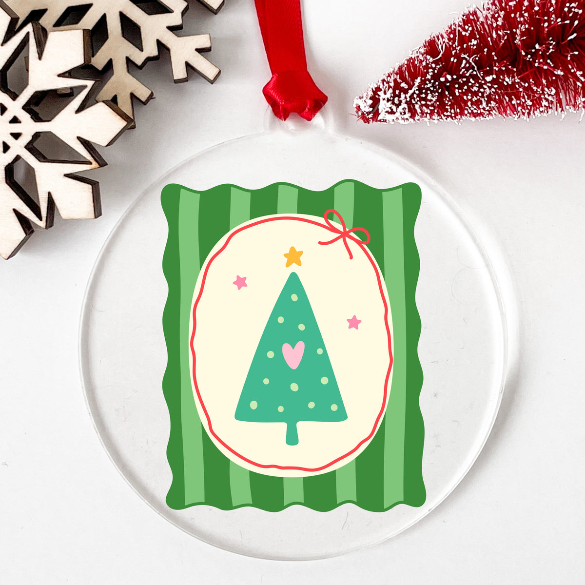 Coquette Teal Heart Christmas Tree UV DTF sticker applied to a clear round acrylic ornament with a red ribbon