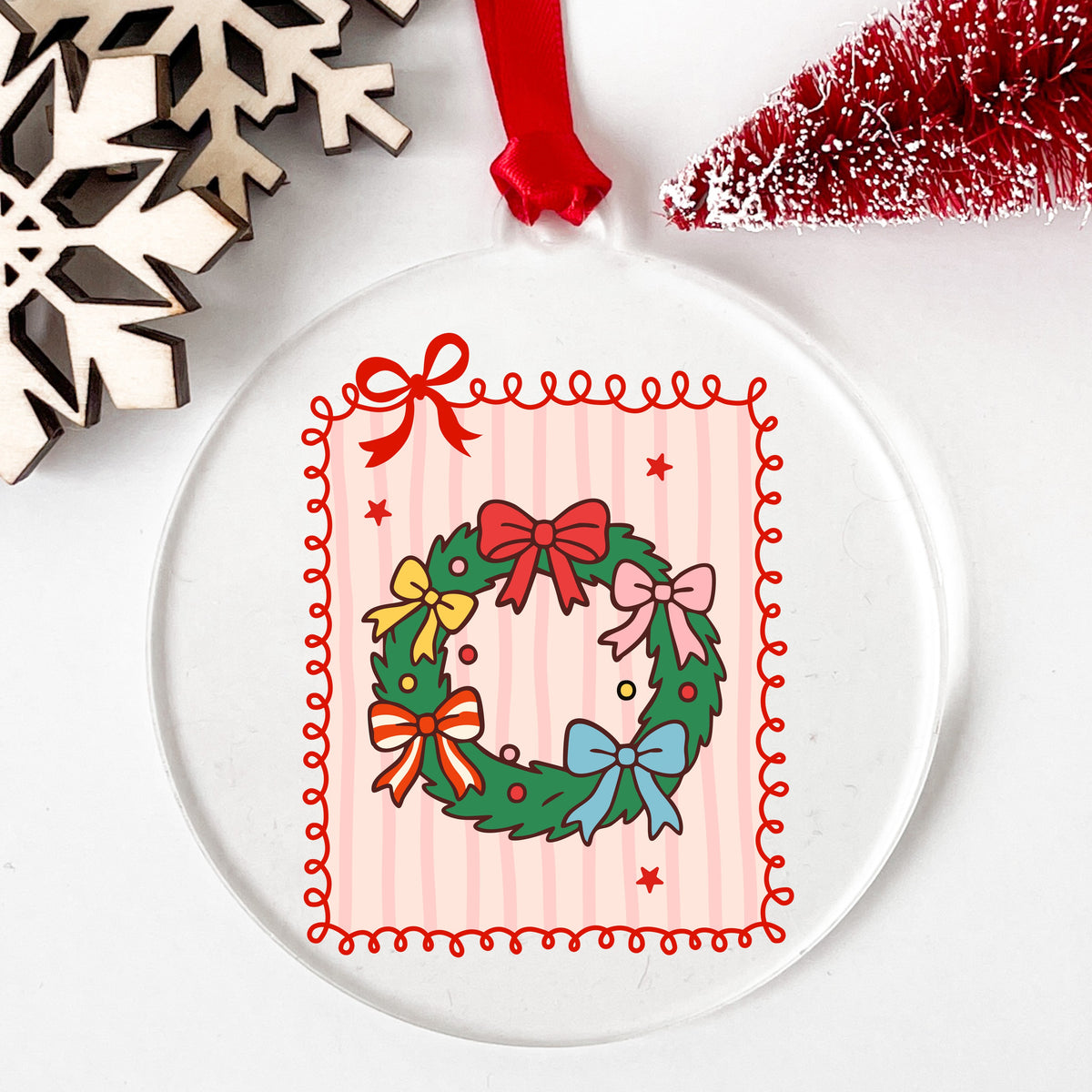 Coquette Bow Christmas Wreath UV DTF sticker applied to a clear round acrylic ornament with a red ribbon