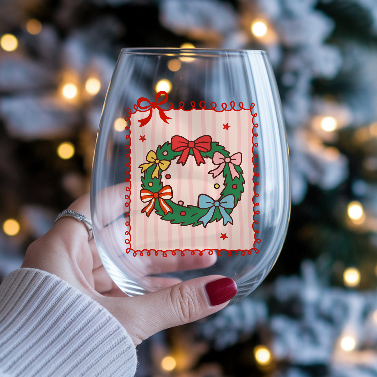 Coquette Bow Christmas Wreath UV DTF sticker applied to a stemless wine glass held in hand