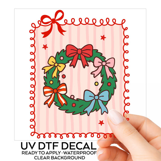 Coquette Bow Christmas Wreath UV DTF sticker on its backing card, held in hand