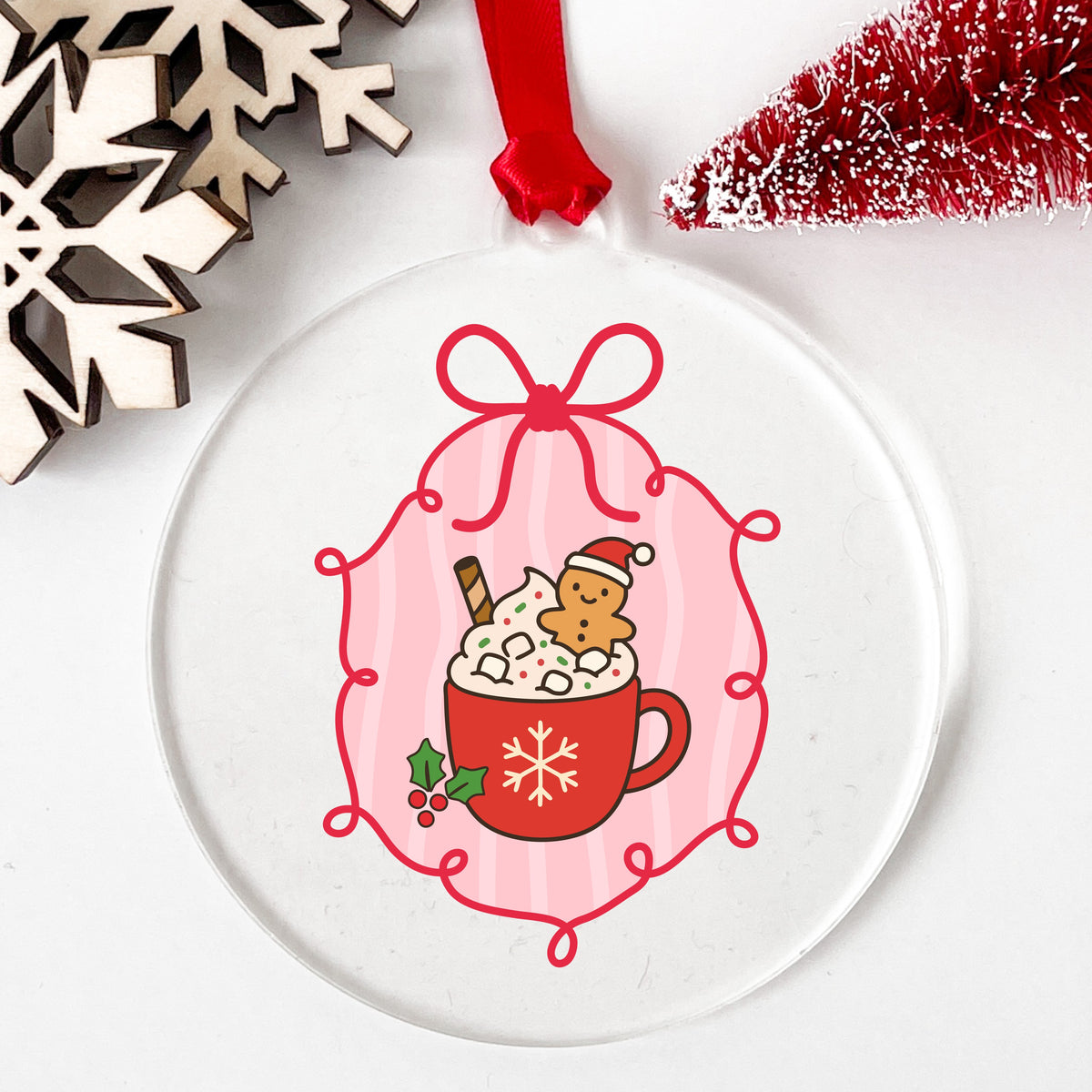 Coquette Gingerbread Hot Cocoa UV DTF sticker applied to a clear round acrylic ornament with a red ribbon