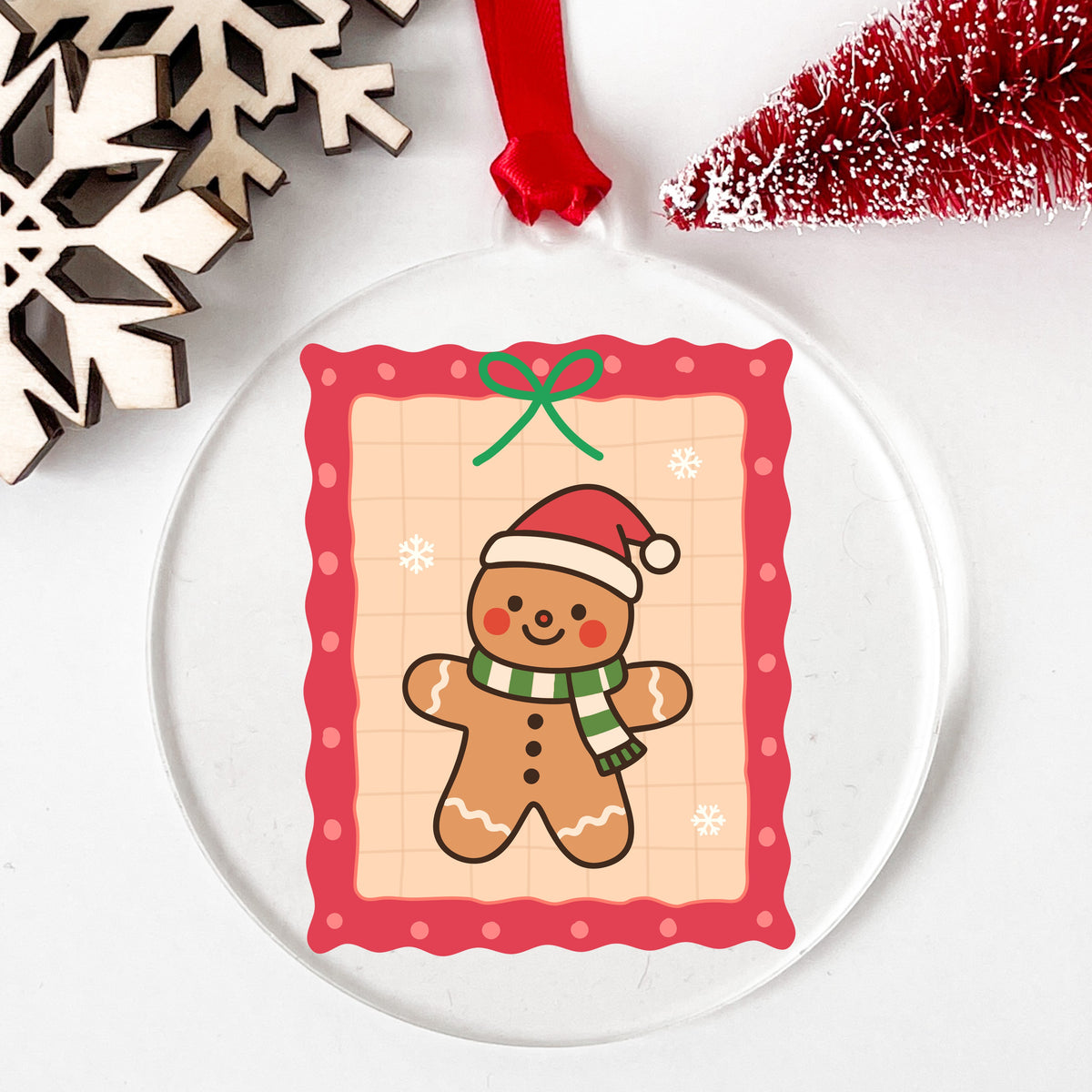 Coquette Gingerbread Man UV DTF sticker applied to a clear round acrylic ornament with a red ribbon