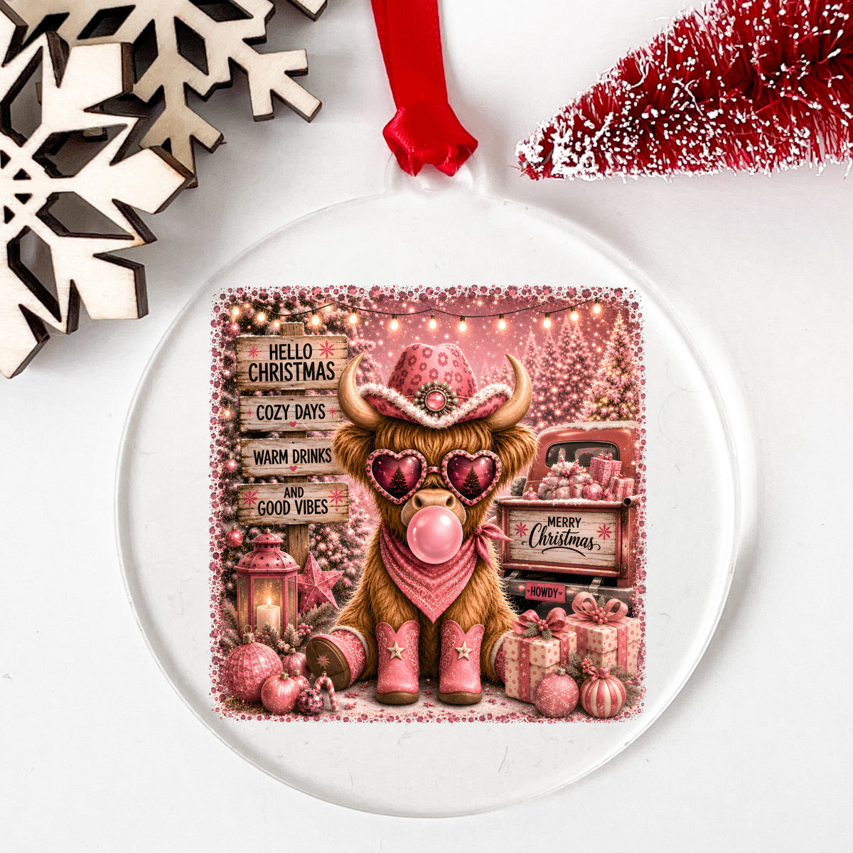 Pink Highland Cow Hello Christmas UV DTF sticker applied to a clear round acrylic ornament with a red ribbon