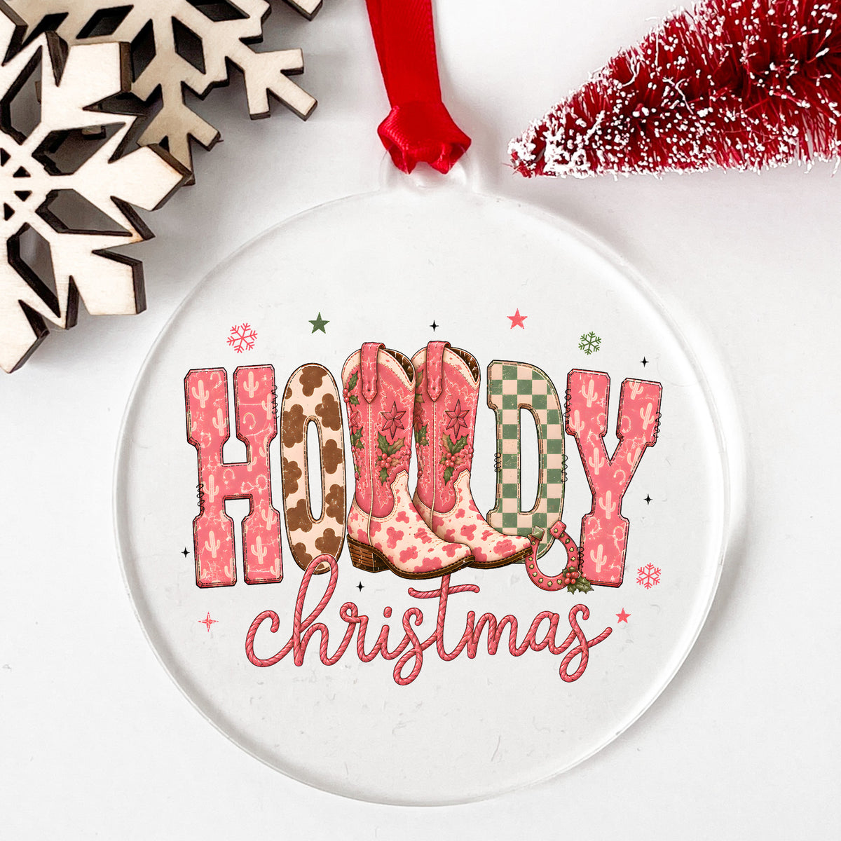 Howdy Christmas Cowboy Boots UV DTF sticker applied to a clear round acrylic ornament with a red ribbon