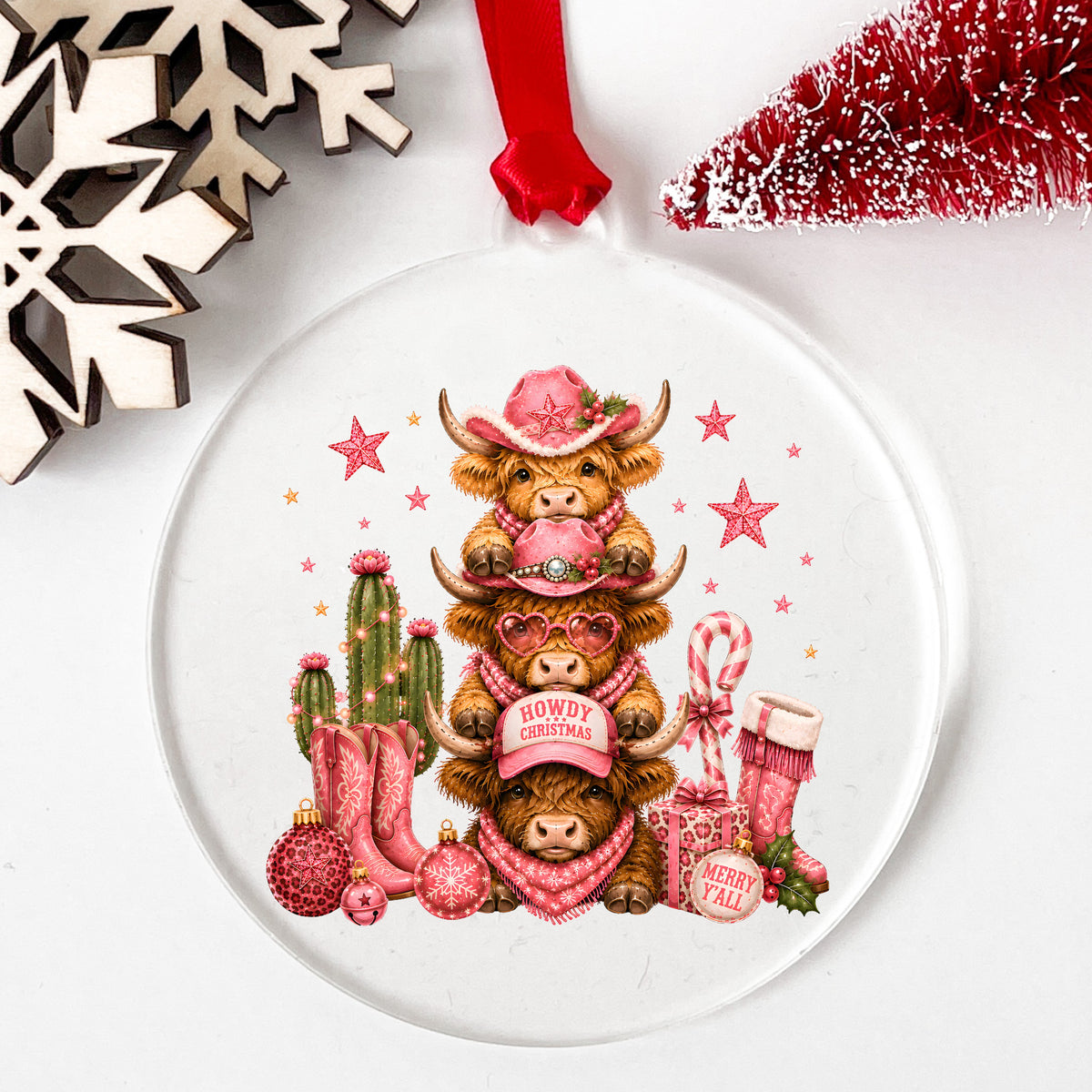 Stacked Highland Cows Howdy Christmas UV DTF sticker applied to a clear round acrylic ornament with a red ribbon