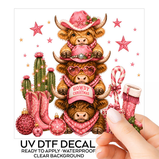 Stacked Highland Cows Howdy Christmas UV DTF sticker on its backing card, held in hand