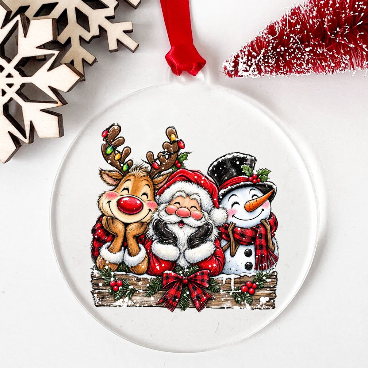 Santa Reindeer Snowman Plaid Bow UV DTF sticker applied to a clear round acrylic ornament with a red ribbon