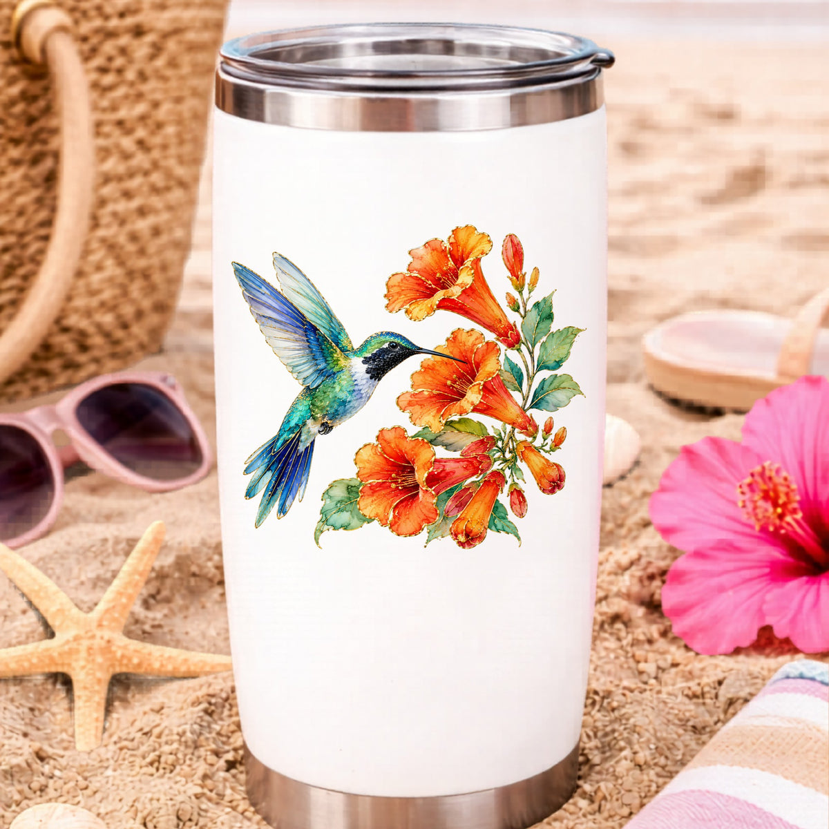 Blue Hummingbird Trumpet Flowers UV DTF sticker applied to a white travel tumbler on beach sand