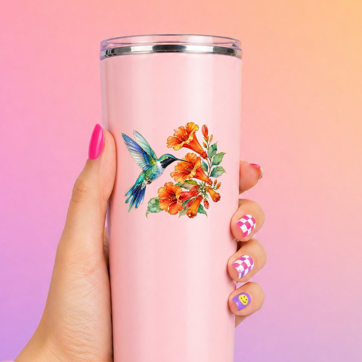 Blue Hummingbird Trumpet Flowers UV DTF sticker applied to a tall pink tumbler on a pink and orange background