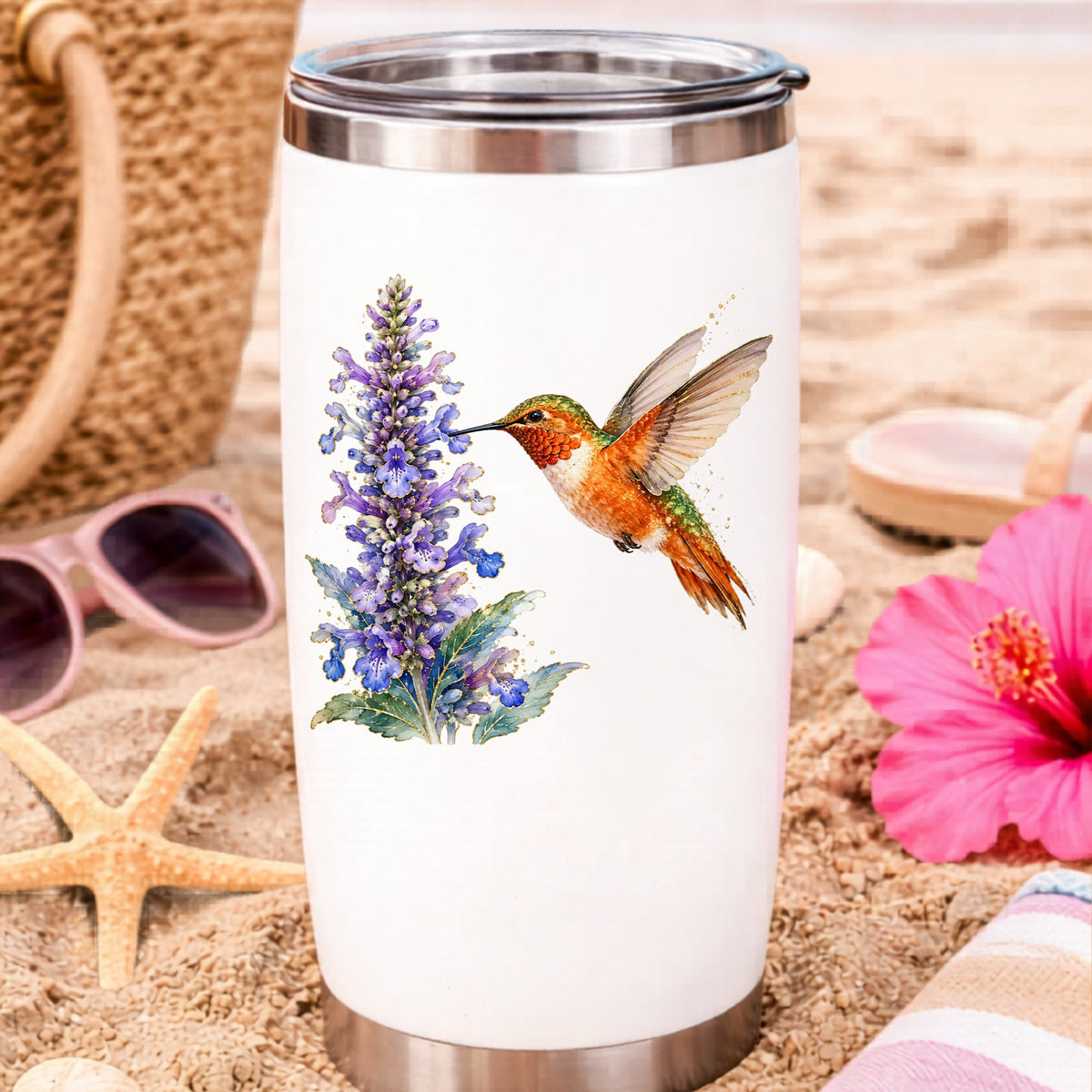 Rufous Hummingbird Purple Flowers UV DTF sticker applied to a white travel tumbler on beach sand