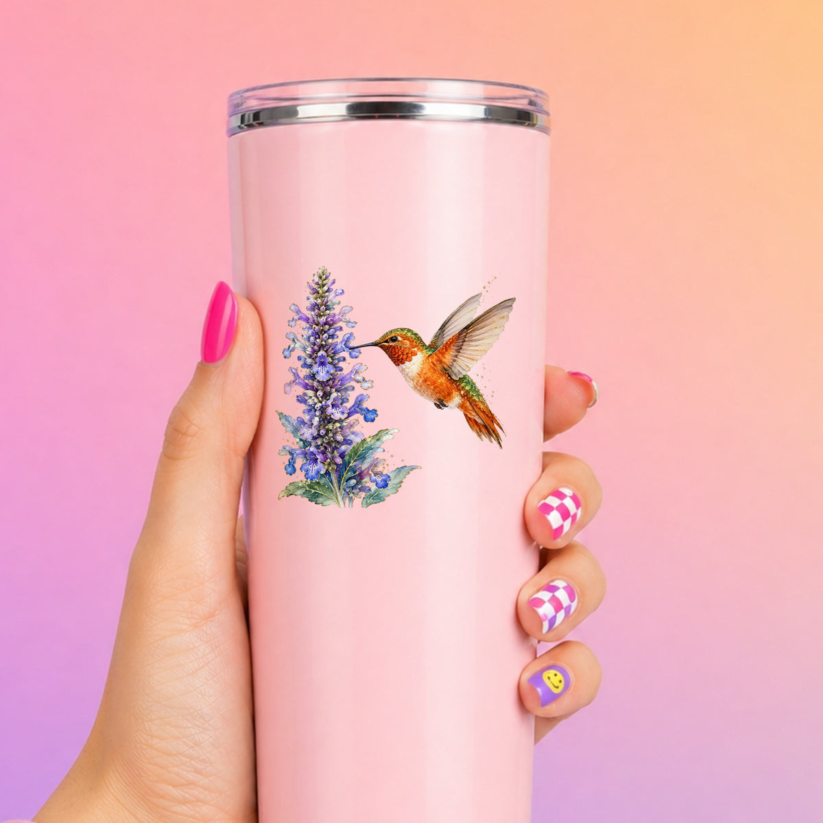 Rufous Hummingbird Purple Flowers UV DTF sticker applied to a tall pink tumbler on a pink and orange background