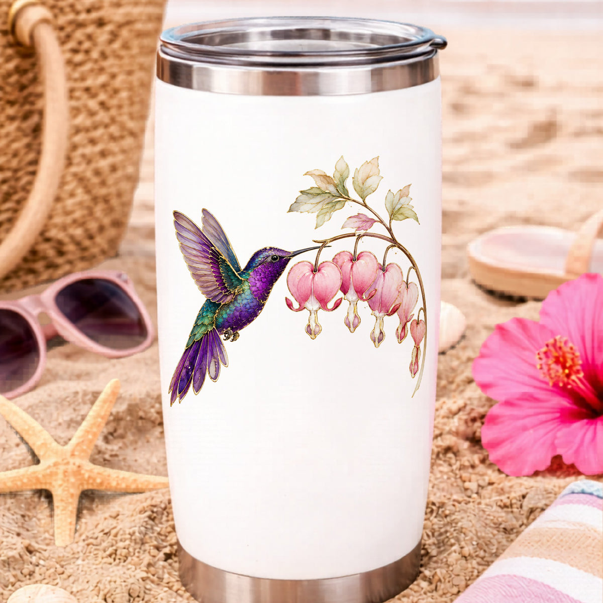 Purple Hummingbird Bleeding Heart UV DTF sticker applied to a white travel tumbler on beach sand