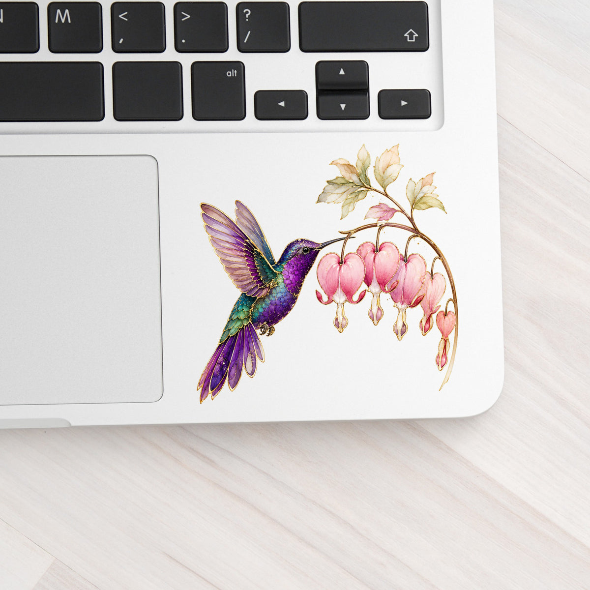 Purple Hummingbird Bleeding Heart UV DTF sticker applied to a silver laptop beside the keyboard