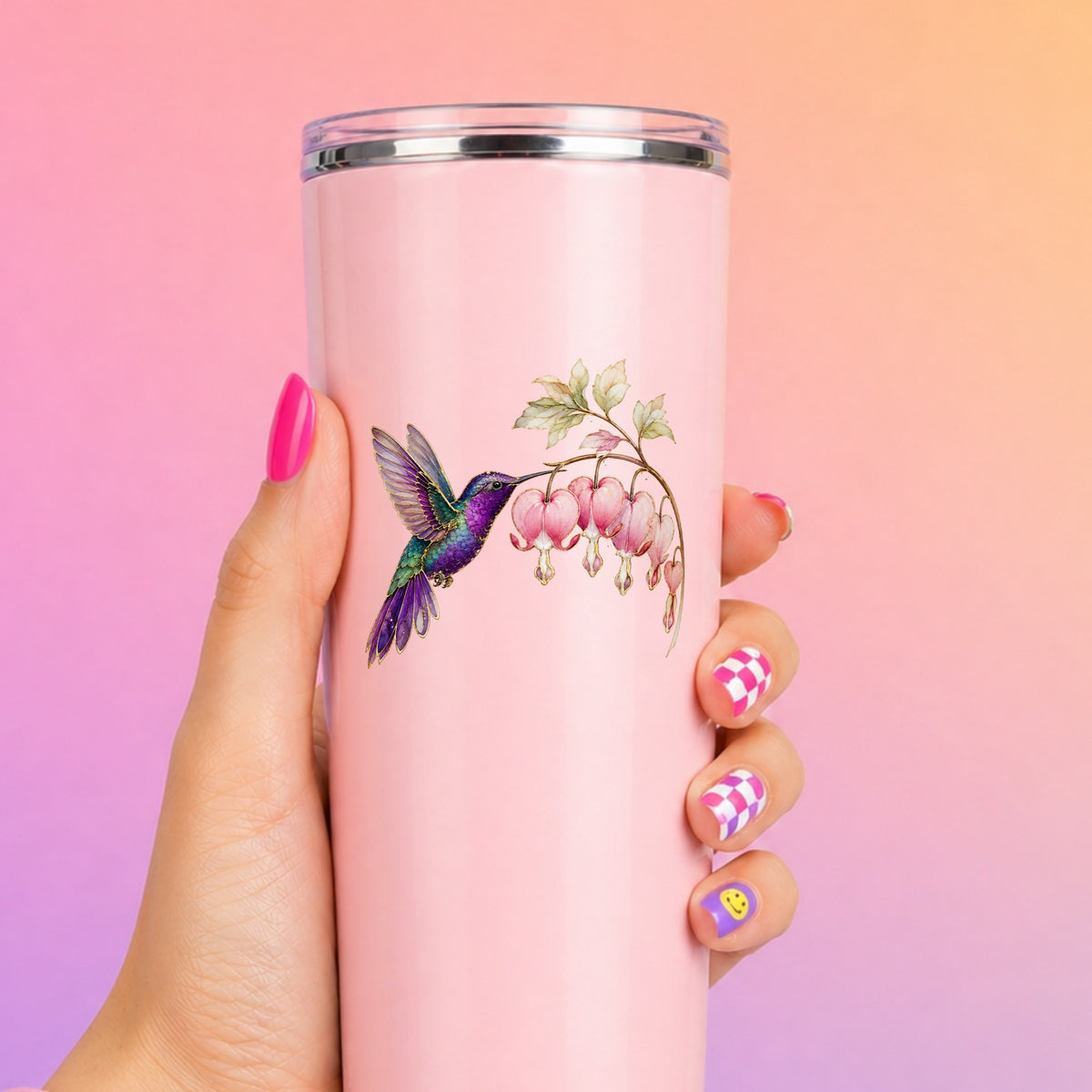 Purple Hummingbird Bleeding Heart UV DTF sticker applied to a tall pink tumbler on a pink and orange background