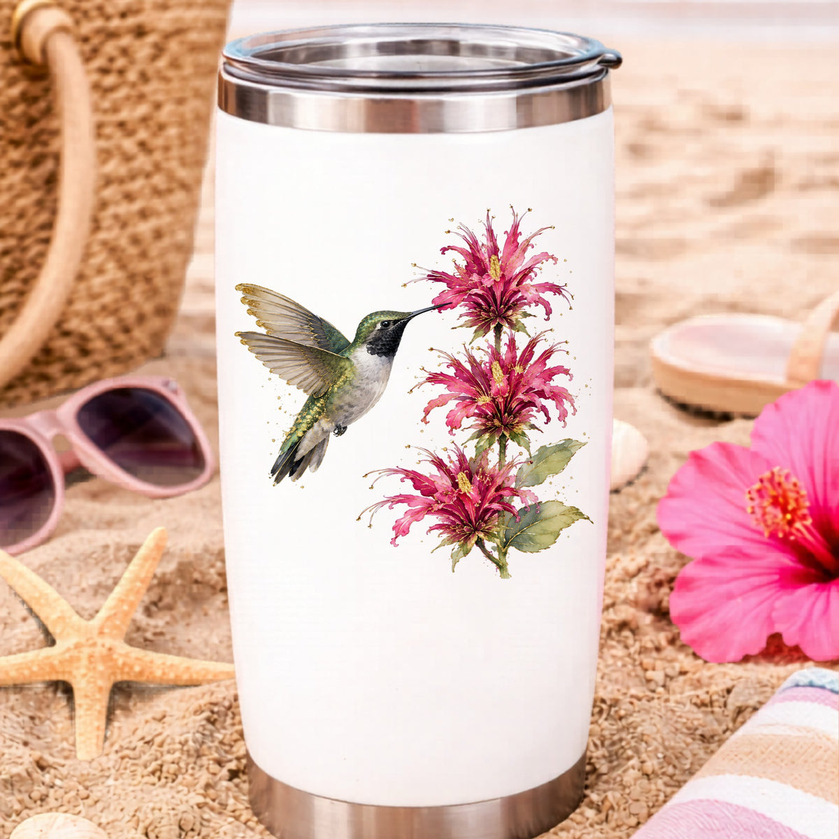 Hummingbird Pink Bee Balm UV DTF sticker applied to a white travel tumbler on beach sand