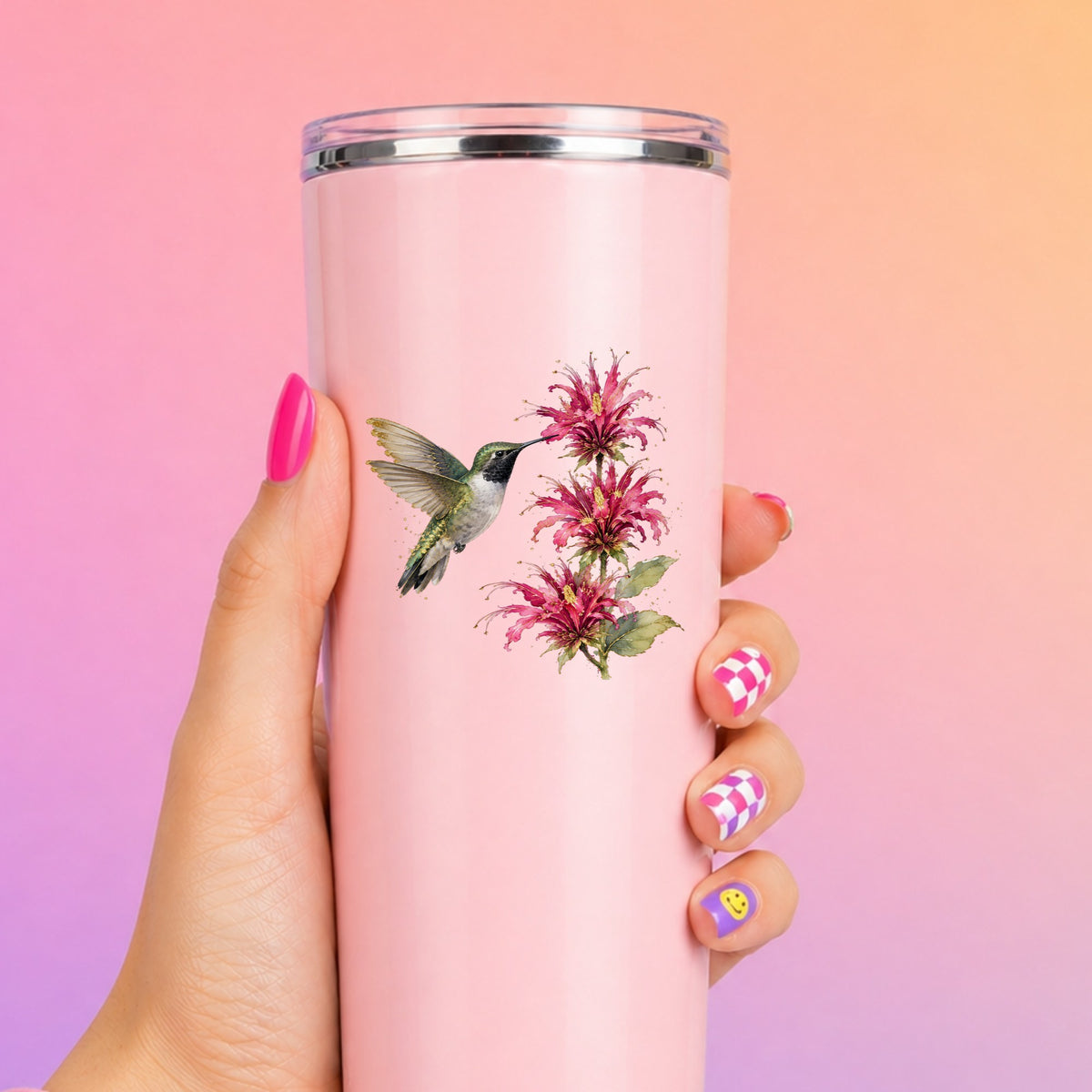 Hummingbird Pink Bee Balm UV DTF sticker applied to a tall pink tumbler on a pink and orange background