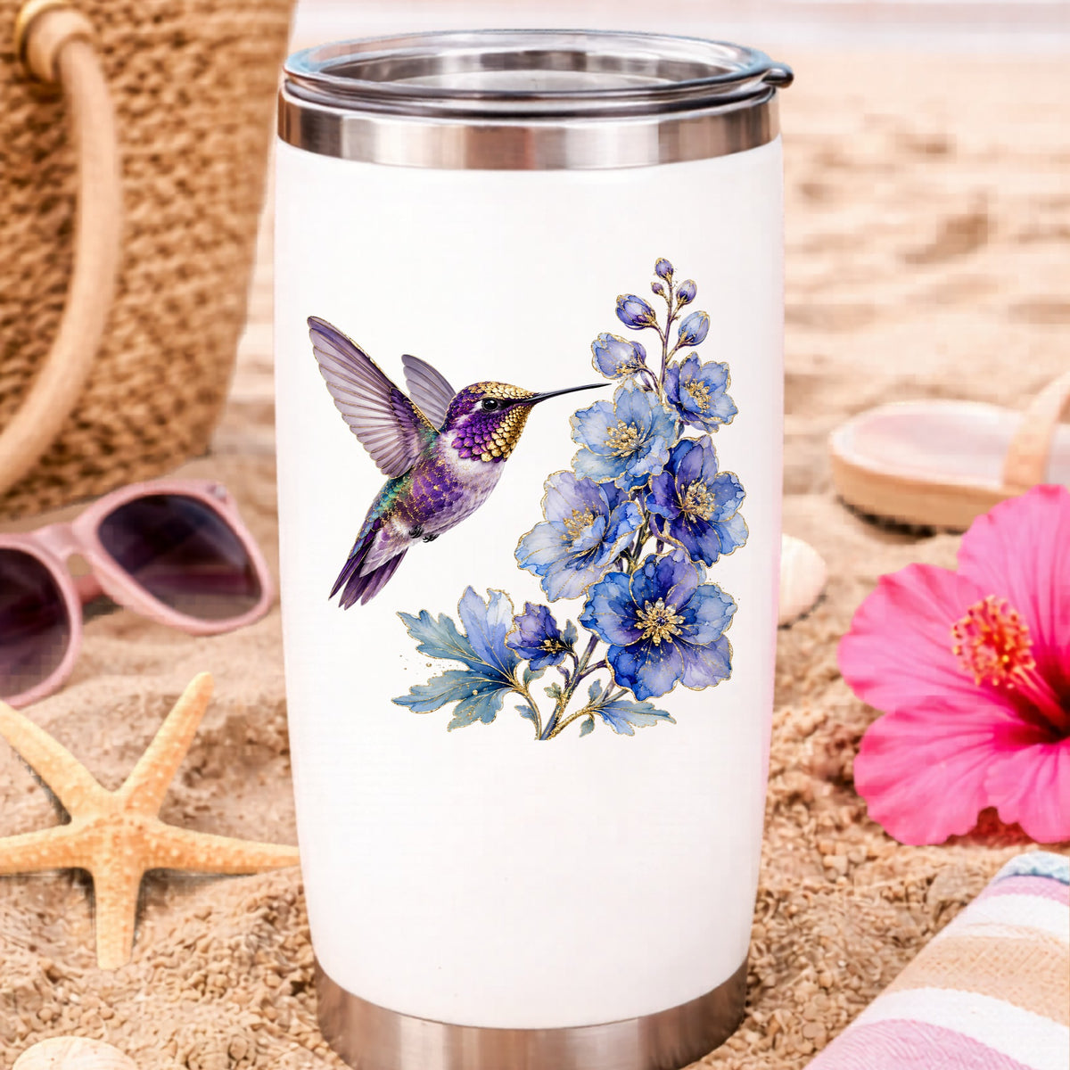Purple Hummingbird Blue Delphinium UV DTF sticker applied to a white travel tumbler on beach sand