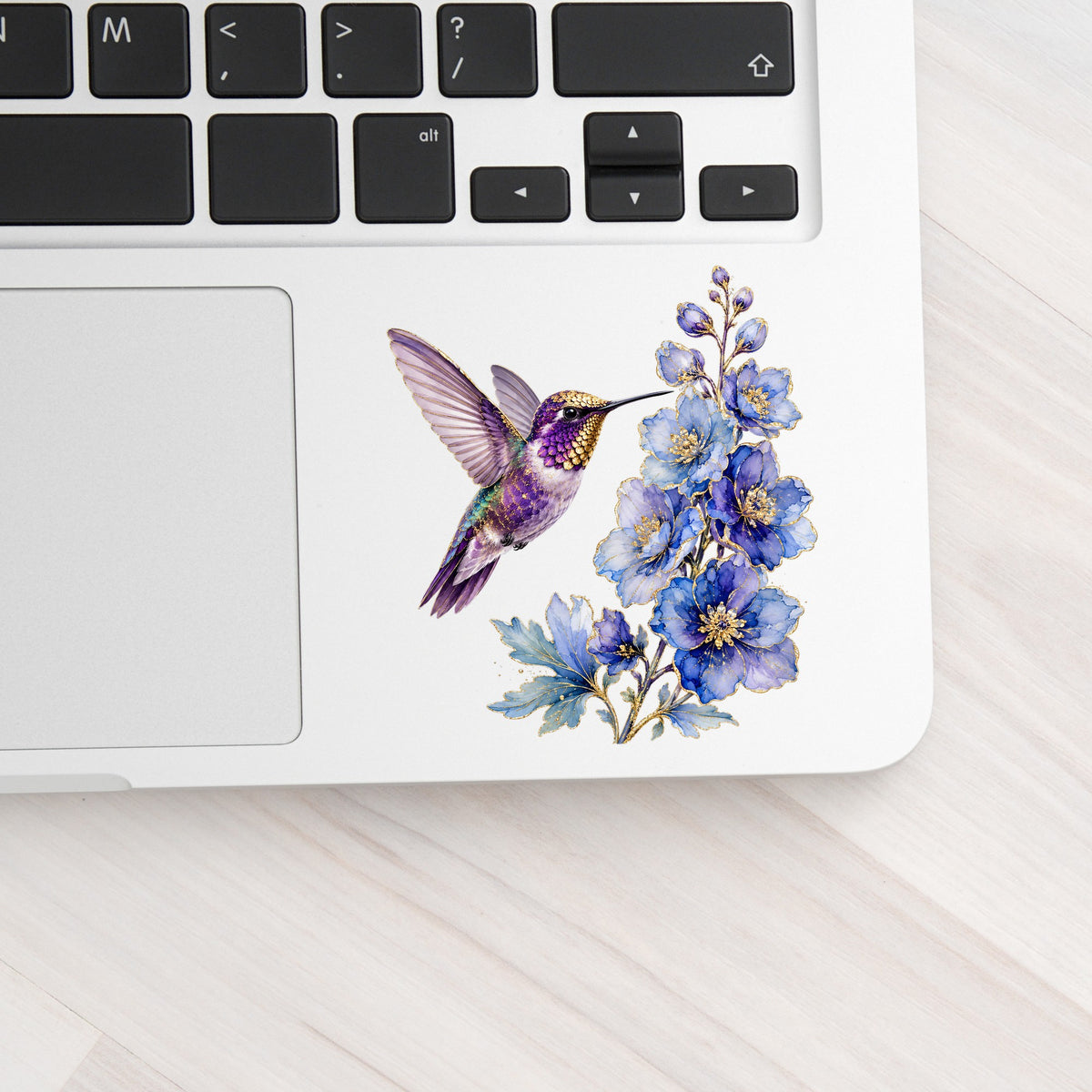 Purple Hummingbird Blue Delphinium UV DTF sticker applied to a silver laptop beside the keyboard