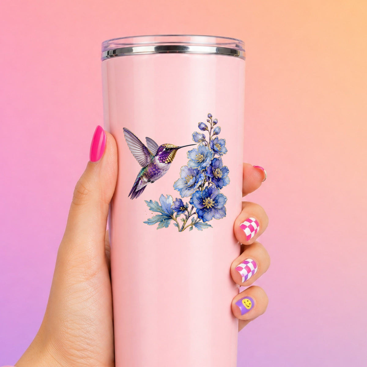 Purple Hummingbird Blue Delphinium UV DTF sticker applied to a tall pink tumbler on a pink and orange background